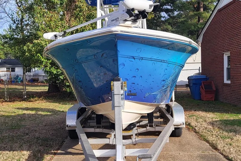 Slide: The Image of 2012 Sea Fox 216 boat on trailer, parked in driveway, surrounded by trees and a brick house. - 2