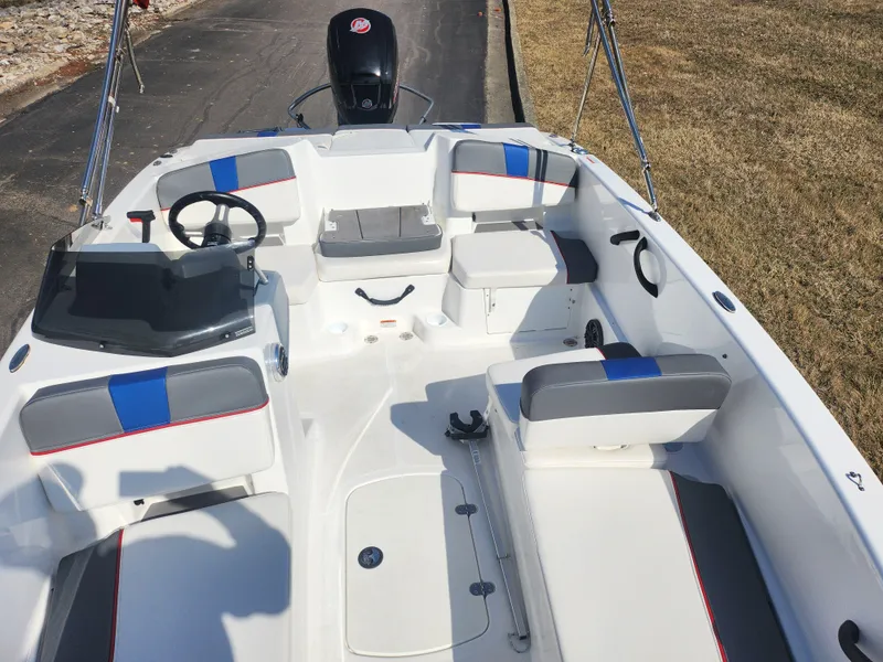 Slide: The Image of 2023 Tahoe T18 boat interior with seating and steering wheel, parked on a paved path. - 17