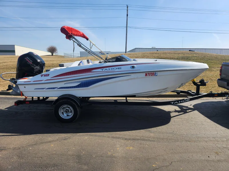 Slide: The Image of 2023 Tahoe T18 boat on trailer, white with red and blue accents, parked outdoors. - 4