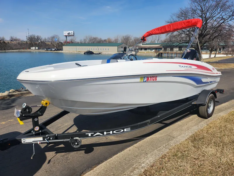 Slide: The Image of 2023 Tahoe T18 boat with red canopy on trailer by a lake. - 8