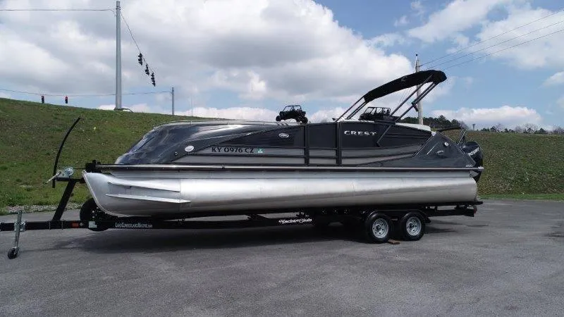 Slide: The Image of 2018 Crest Savannah 250 NX-L pontoon boat on trailer, parked outdoors under cloudy sky. - 10