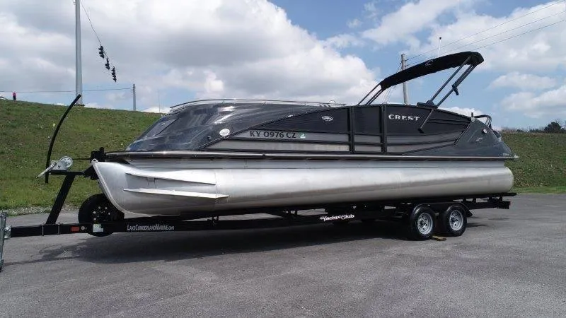 Slide: The Image of 2018 Crest Savannah 250 NX-L pontoon boat on trailer, parked outdoors under cloudy sky. - 11
