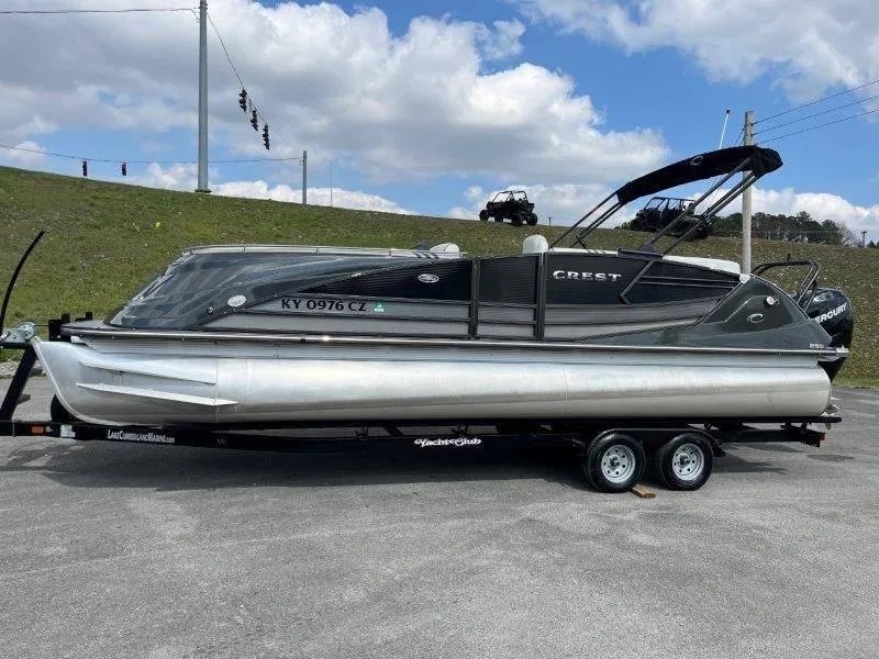 Slide: The Image of 2018 Crest Savannah 250 NX-L pontoon boat on trailer, parked outdoors under cloudy sky. - 21