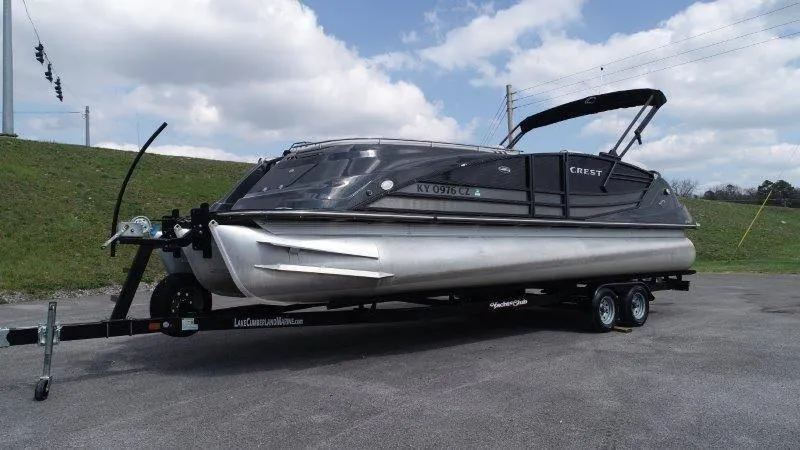 Slide: The Image of 2018 Crest Savannah 250 NX-L pontoon boat on trailer, parked outdoors under cloudy sky. - 9