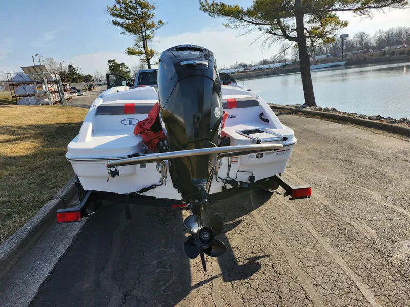 Slide: The Image of 2022 Tahoe T16 boat on trailer by lakeside, rear view with outboard motor. - 2
