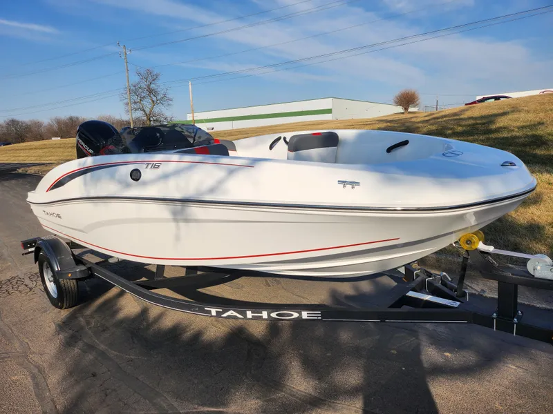 Slide: The Image of 2022 Tahoe T16 boat on trailer, parked outdoors under clear blue sky. - 5