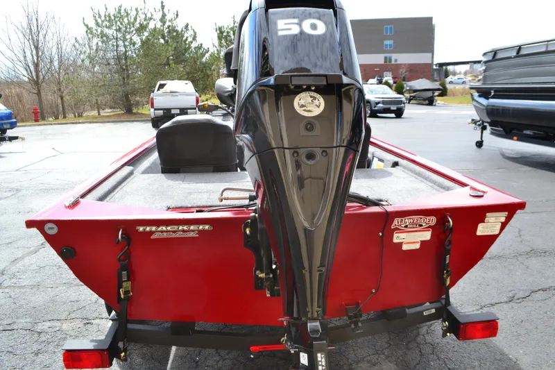 Slide: The Image of 2025 Tracker Pro 170 boat, red exterior, 50 HP engine, parked outdoors. - 2