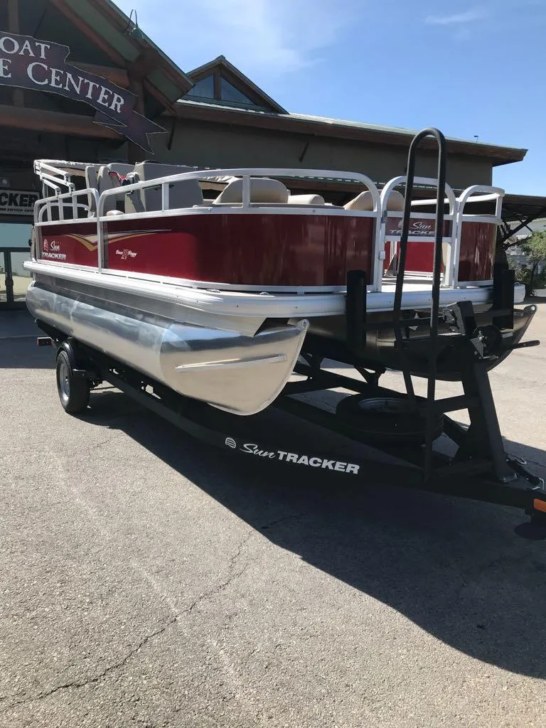 Slide: The Image of 2025 Sun Tracker Bass Buggy 18 DLX pontoon boat on trailer, parked outdoors. - 3