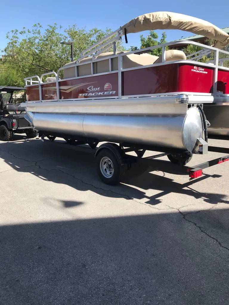 Slide: The Image of 2025 Sun Tracker Bass Buggy 18 DLX pontoon boat on trailer, parked outdoors. - 4