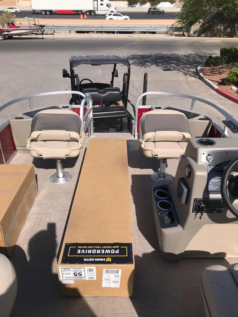 Slide: The Image of 2025 Sun Tracker Bass Buggy 18 DLX interior with seating and console, parked outdoors. - 7