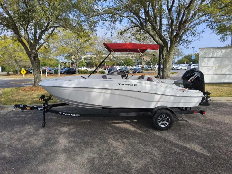 The Image of 2025 Tahoe T18 boat with red canopy on trailer, parked under trees. - 0