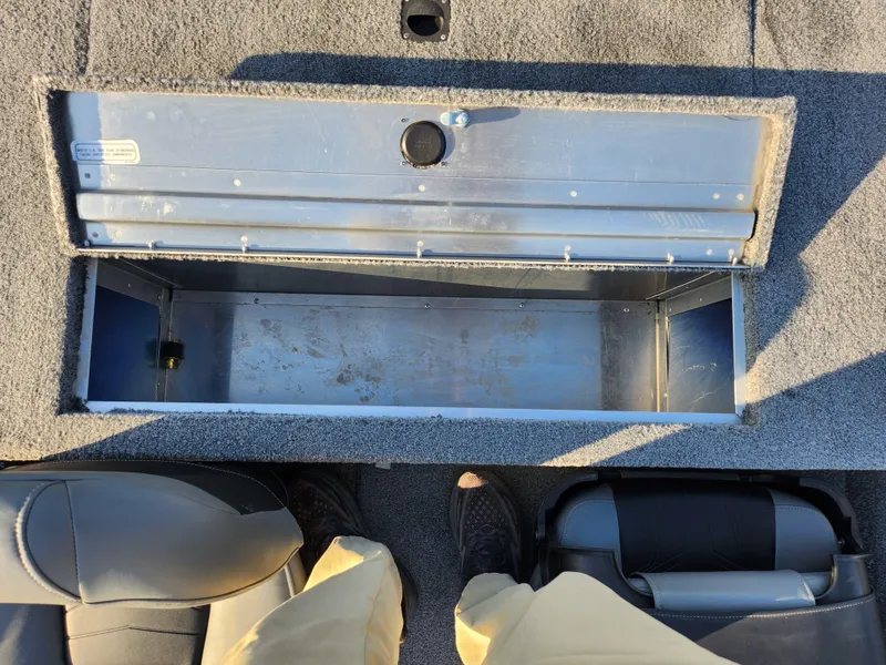 Slide: The Image of Open storage compartment in a 2021 Tracker Pro 170 boat, with gray carpeted interior. - 23