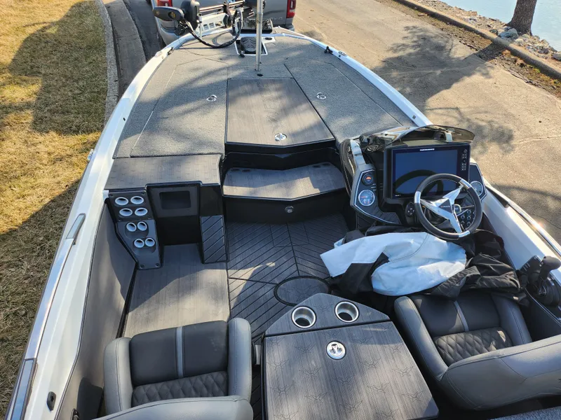 Slide: The Image of 2023 Vexus VX20 boat interior with modern dashboard and seating, parked near a lake. - 11