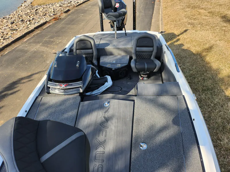 Slide: The Image of 2023 Vexus VX20 boat with spacious deck and seating, parked near a rocky shoreline. - 19