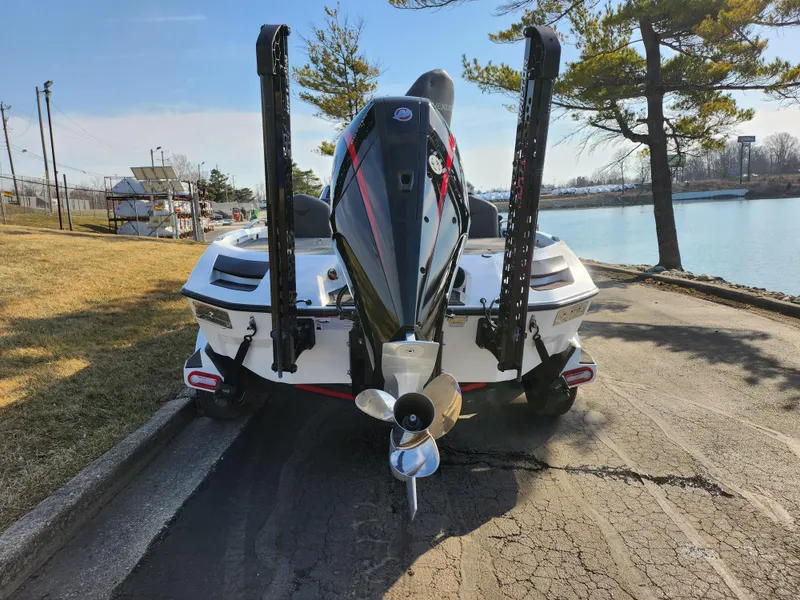 Slide: The Image of 2023 Vexus VX20 boat parked by a lakeside, rear view with motor and power poles. - 2
