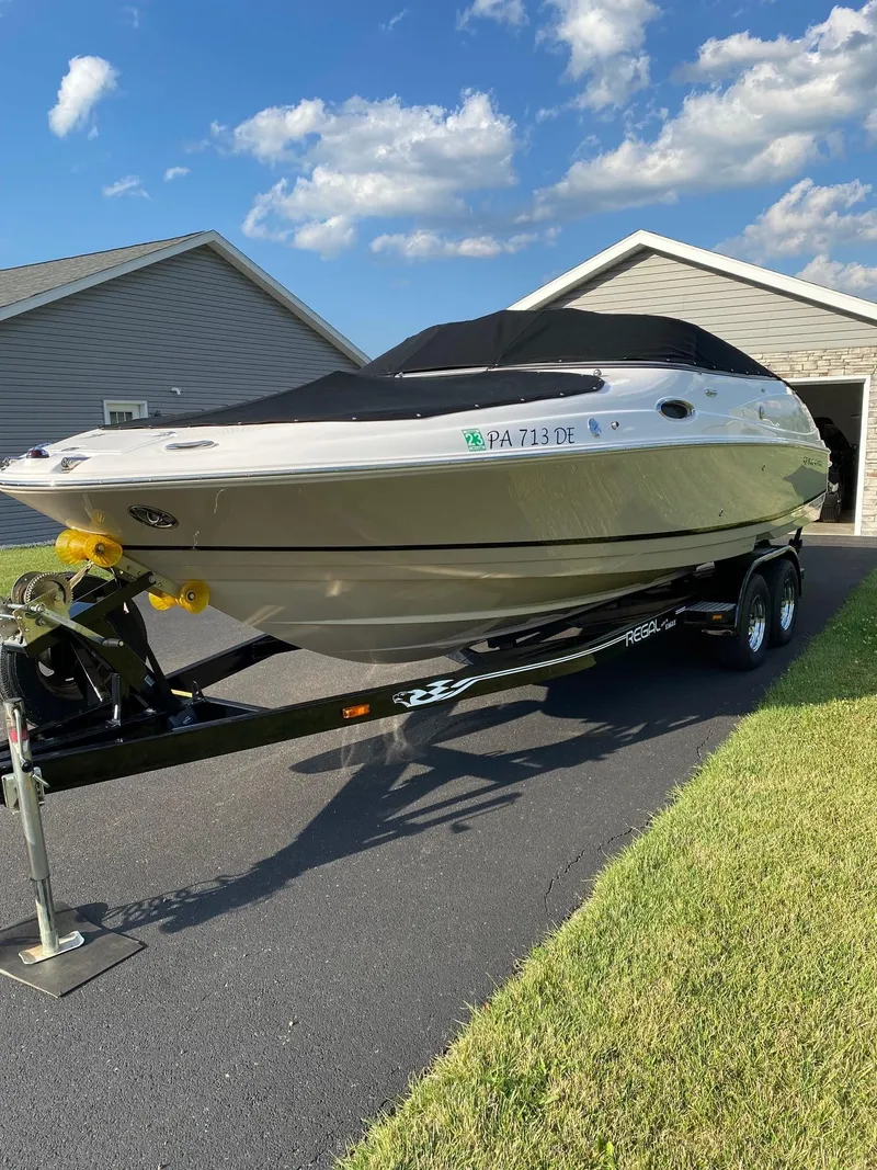 Slide: The Image of 2009 Regal 2400 Bowrider boat on trailer, parked in driveway under blue sky. - 3