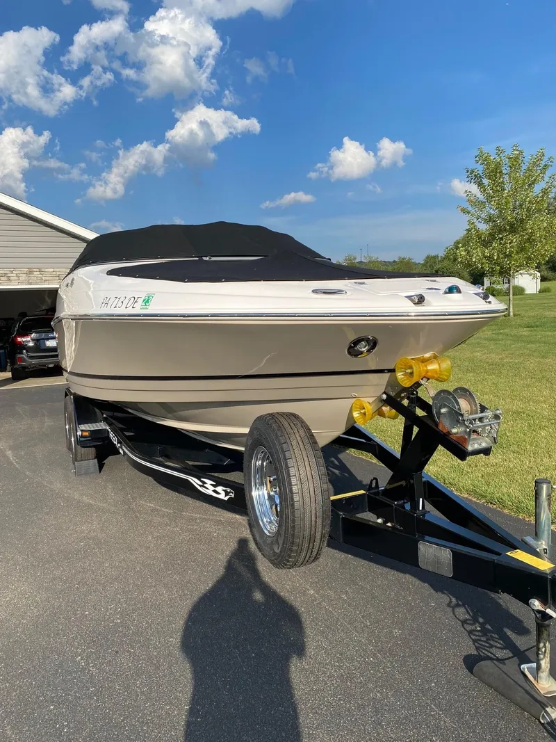 Slide: The Image of 2009 Regal 2400 Bowrider boat on trailer, parked outdoors under a clear blue sky. - 4