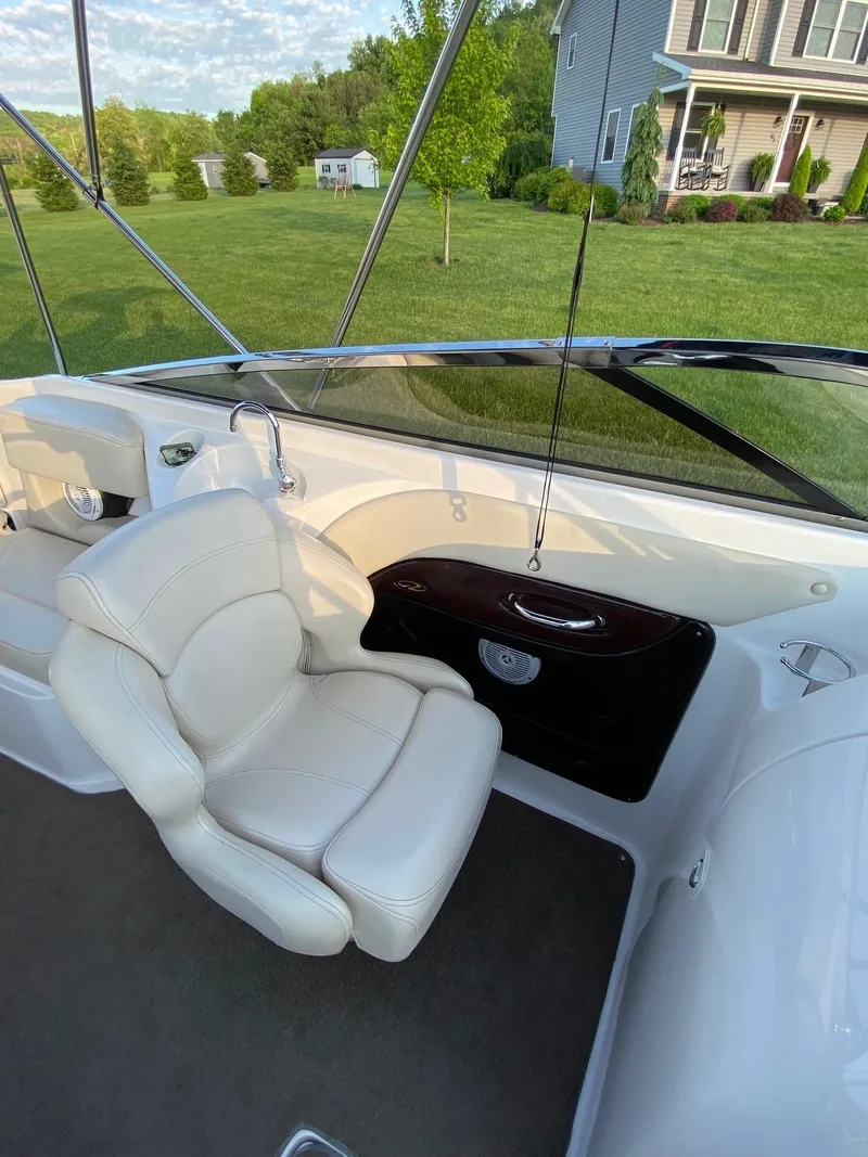 Slide: The Image of 2009 Regal 2400 Bowrider interior with white seating and dashboard, parked near a house. - 7