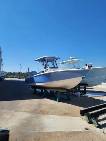 Slide: The Image of 2023 Robalo 266 Cayman boat with Yamaha engine on a lift at a marina. - 2
