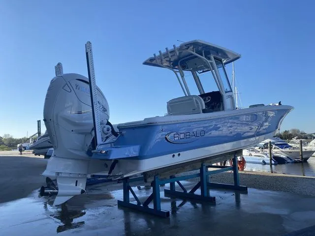 Slide: The Image of 2023 Robalo 266 Cayman boat in blue, docked at a marina. - 4
