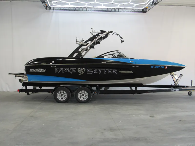 The Image of 2012 Malibu Wakesetter 22 MXZ boat on trailer, black and blue design. - 0