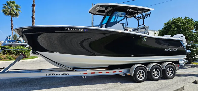 Slide: The Image of 2020 Blackfin 272 CC boat on a trailer, parked outdoors. - 1