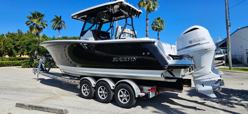 Slide: The Image of 2020 Blackfin 272 CC boat on trailer, parked under clear blue sky. - 2