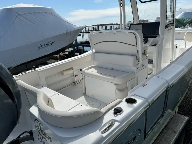 Slide: The Image of 2022 Sea Hunt Ultra 239 SE boat interior with seating and console, docked at marina. - 16