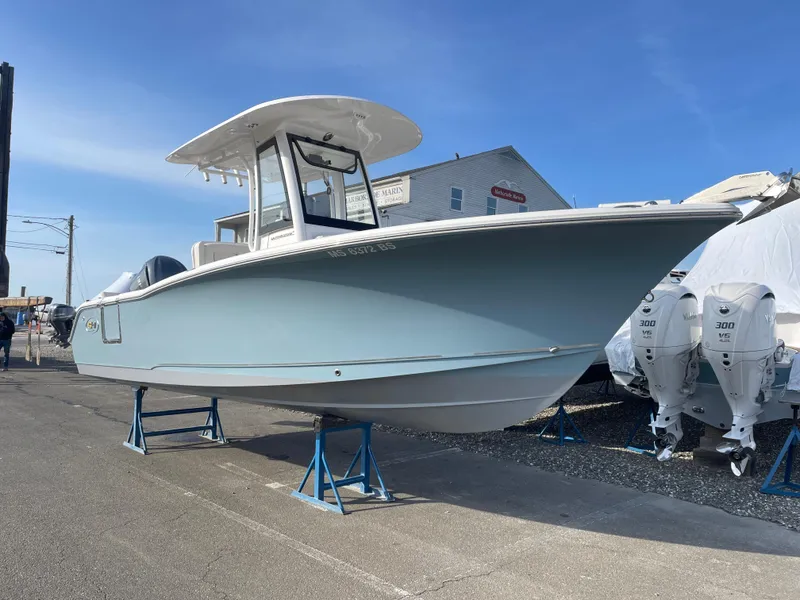Slide: The Image of 2022 Sea Hunt Ultra 239 SE boat on display, light blue hull, elevated on stands. - 2