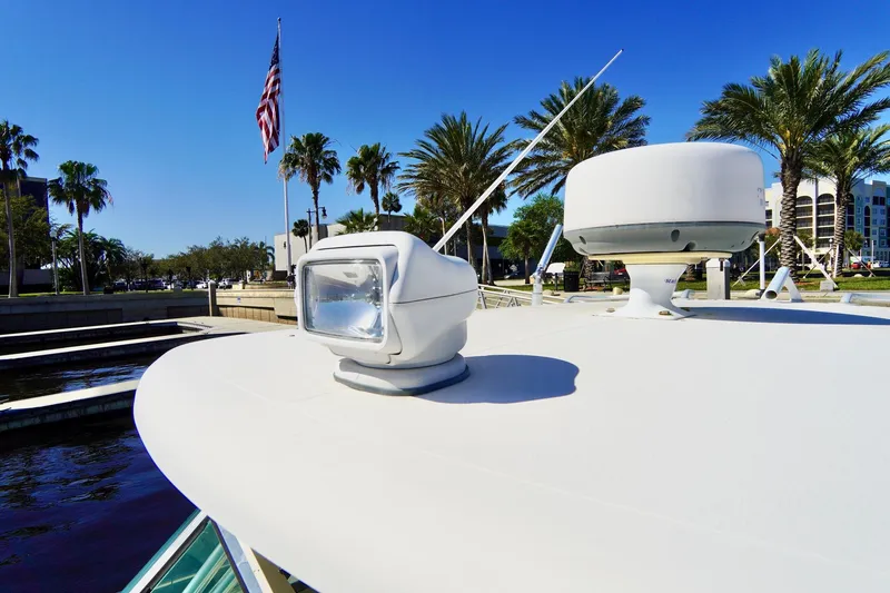 Slide: The Image of 2003 Pursuit 3070 Express boat with radar and spotlight, docked near palm trees and American flag. - 10