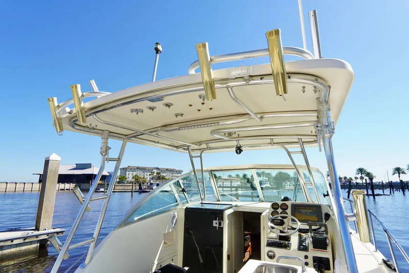 Slide: The Image of 2003 Pursuit 3070 Express boat docked, showcasing helm and fishing rod holders. - 11