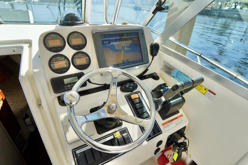 Slide: The Image of 2003 Pursuit 3070 Express boat helm with steering wheel and navigation instruments. - 12
