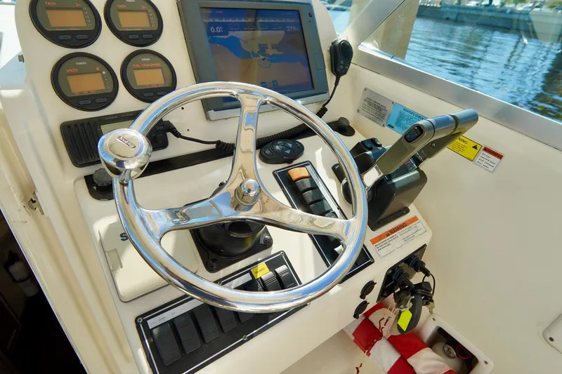 Slide: The Image of Control panel of 2003 Pursuit 3070 Express boat with steering wheel and navigation instruments. - 16