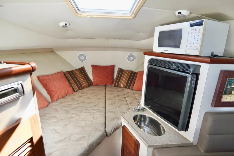 Slide: The Image of 2003 Pursuit 3070 Express cabin interior with bed, microwave, and sink. - 23