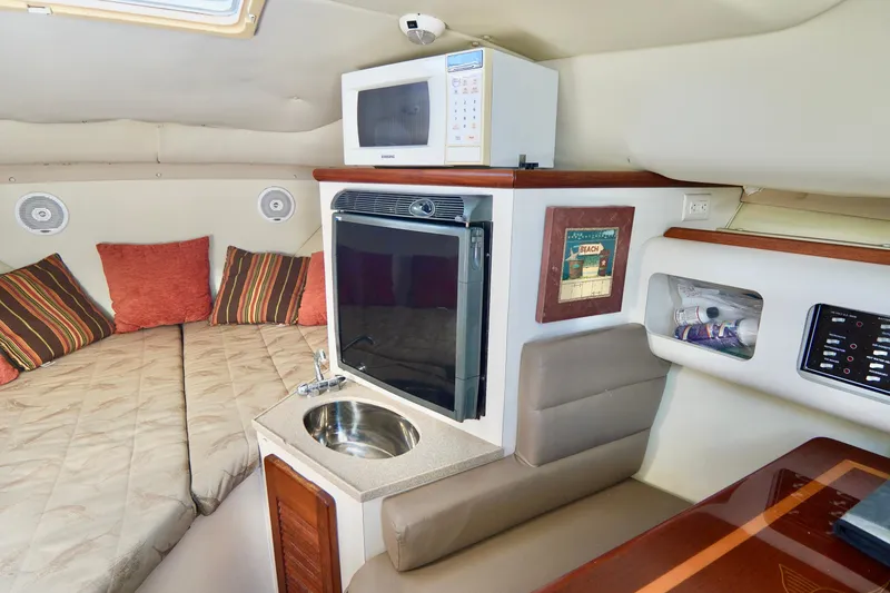 Slide: The Image of 2003 Pursuit 3070 Express cabin interior with bed, microwave, and sink. - 24
