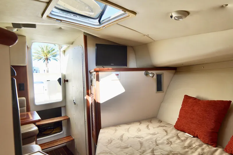 Slide: The Image of 2003 Pursuit 3070 Express cabin interior with bed, TV, and skylight. - 26