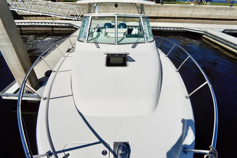 Slide: The Image of 2003 Pursuit 3070 Express boat docked, showcasing sleek design and spacious deck. - 6