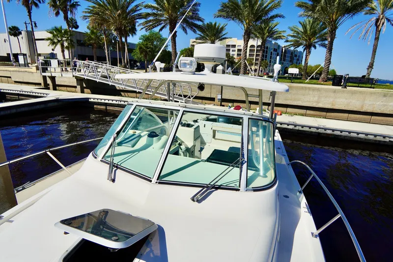 Slide: The Image of 2003 Pursuit 3070 Express boat docked near palm trees and waterfront buildings. - 8