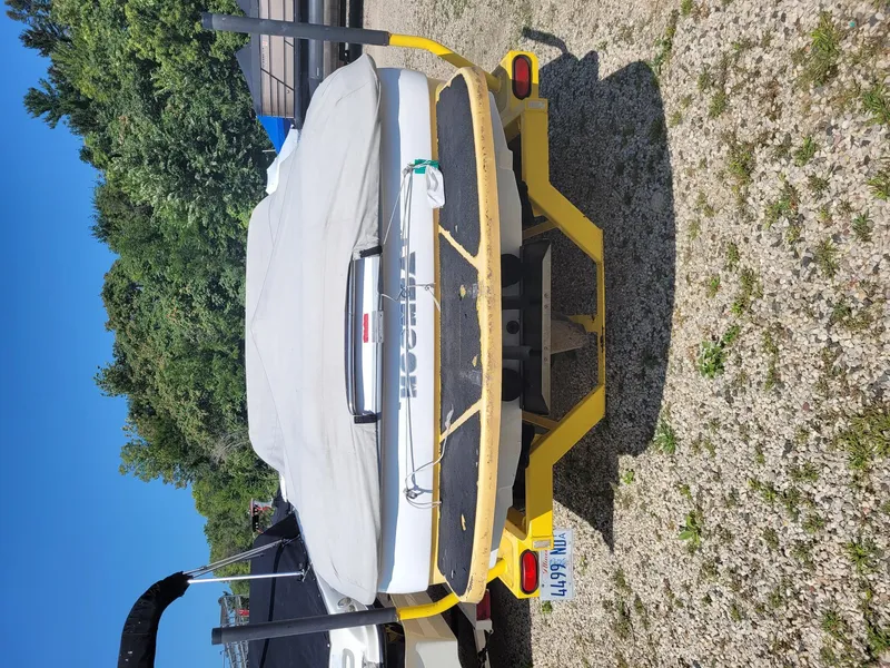 Slide: The Image of 2002 Moomba Outback LSV boat on yellow trailer, covered, parked on gravel. - 15