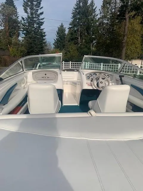 Slide: The Image of 1998 Sea Ray 185 Bow Rider interior with white seats and steering wheel, surrounded by trees. - 8