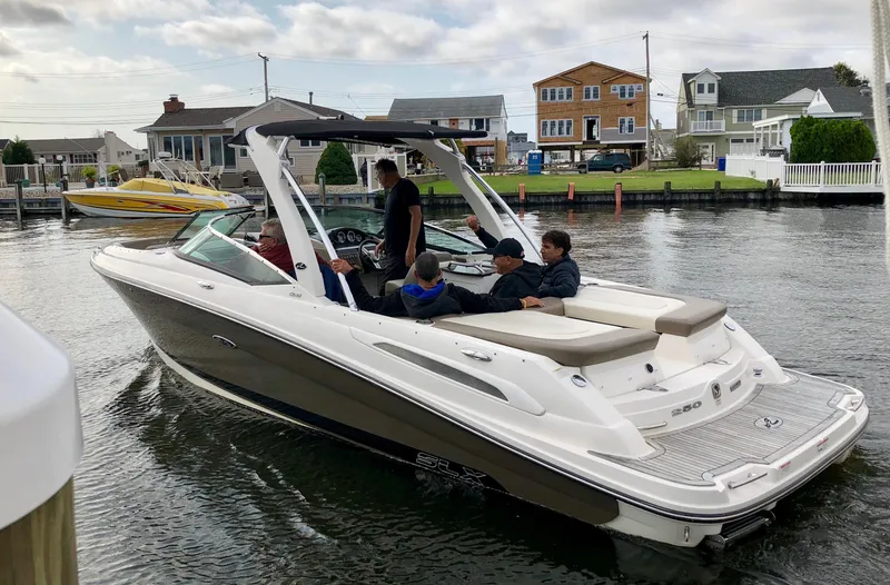 Slide: The Image of 2013 Sea Ray 250 SLX boat cruising on a calm residential waterway. - 10