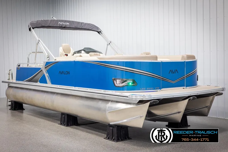 Slide: The Image of 2025 Avalon LSZ VRB pontoon boat in a showroom, featuring a sleek blue design. - 2
