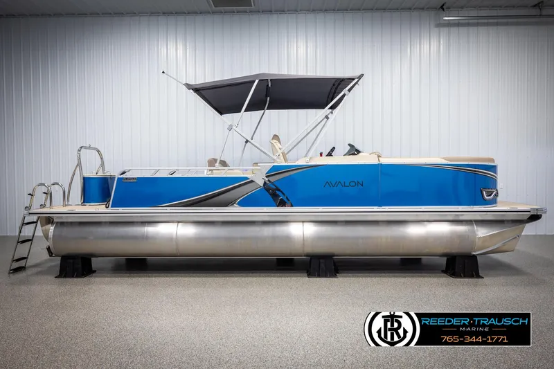 Slide: The Image of 2025 Avalon LSZ VRB pontoon boat with blue exterior and canopy in showroom. - 5