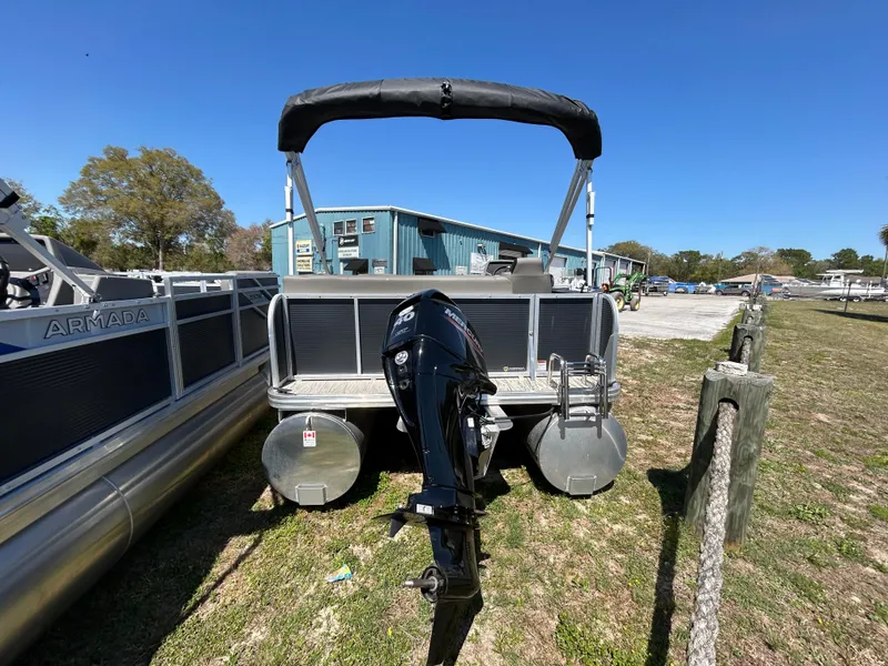 Slide: The Image of 2025 Armada Z-168 pontoon boat with outboard motor, parked on grass under clear blue sky. - 16