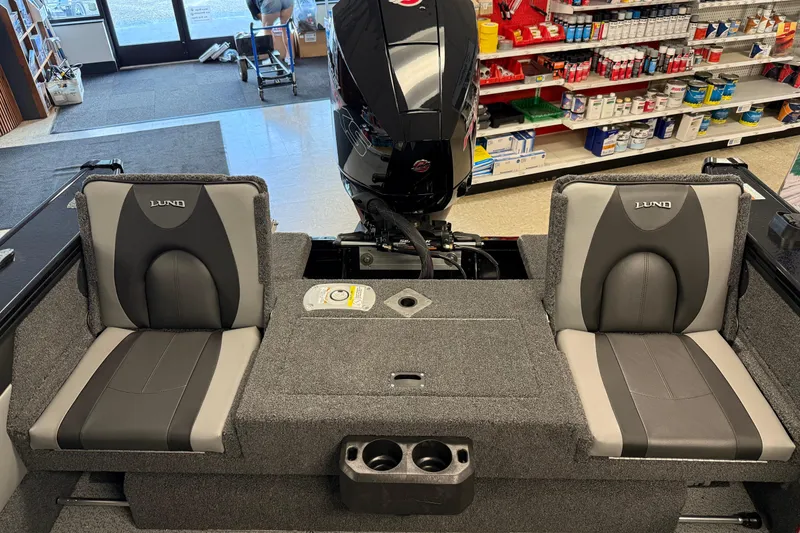 Slide: The Image of 2025 Lund 1875 Crossover XS boat interior with gray seating and motor, displayed in a store. - 7