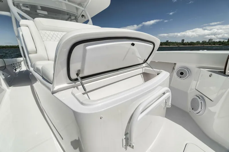 Slide: The Image of 2023 Jupiter 40 boat interior with open storage compartment, white seating, and ocean view. - 16