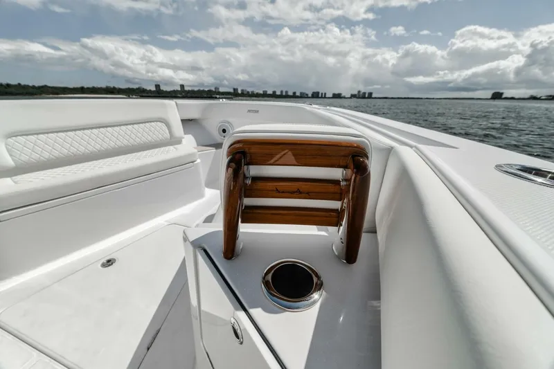 Slide: The Image of 2023 Jupiter 40 boat interior with white seating and wooden accents on a sunny day. - 18