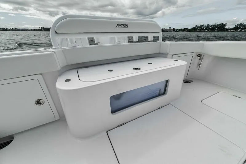 Slide: The Image of 2023 Jupiter 40 boat interior with storage compartment and rod holders, on calm water. - 32