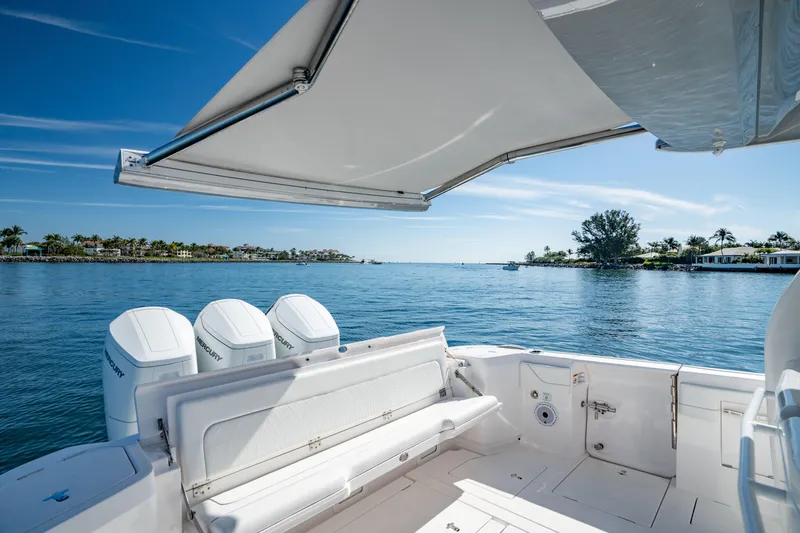 Slide: The Image of 2023 Intrepid 427 Nomad SE boat with canopy, overlooking serene blue waters. - 27