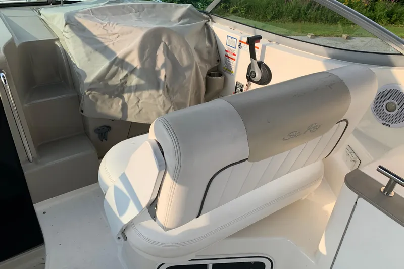 Slide: The Image of 2010 Sea Ray 260 Sundancer cockpit with white seating and covered controls. - 26
